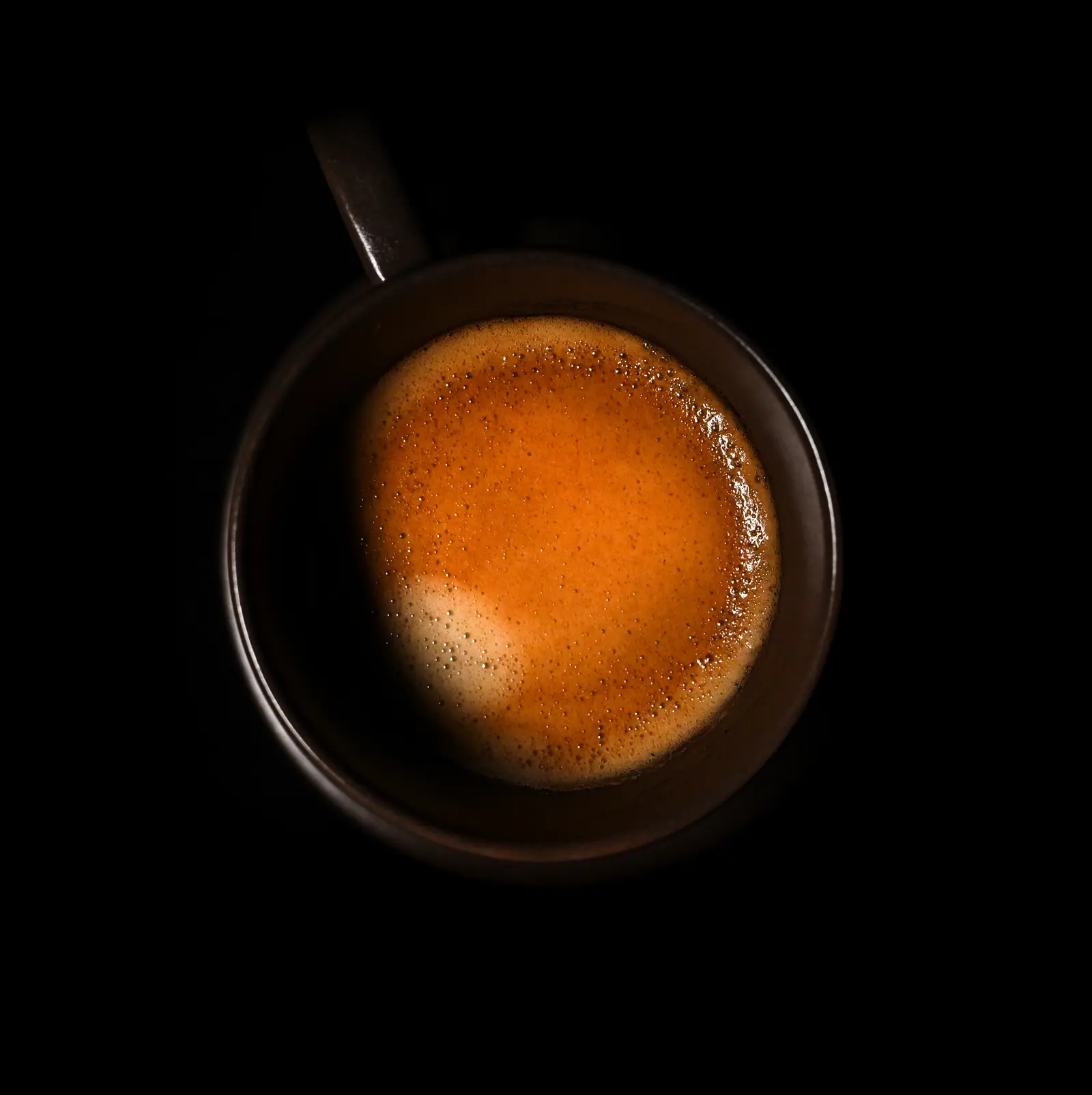 An espresso seen from above, on a black background