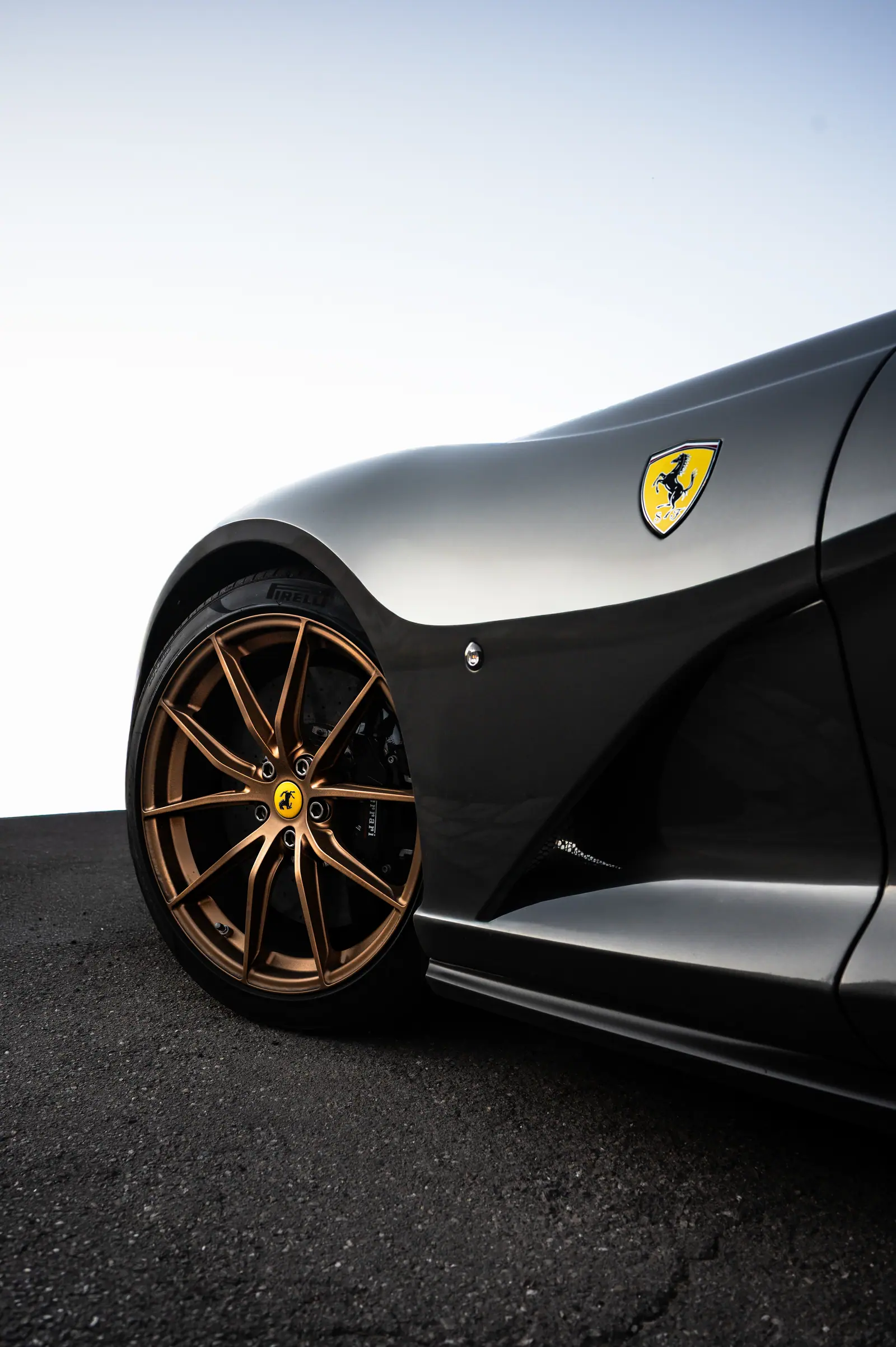 Ferrari badge and bronze wheel on a dark grey car
