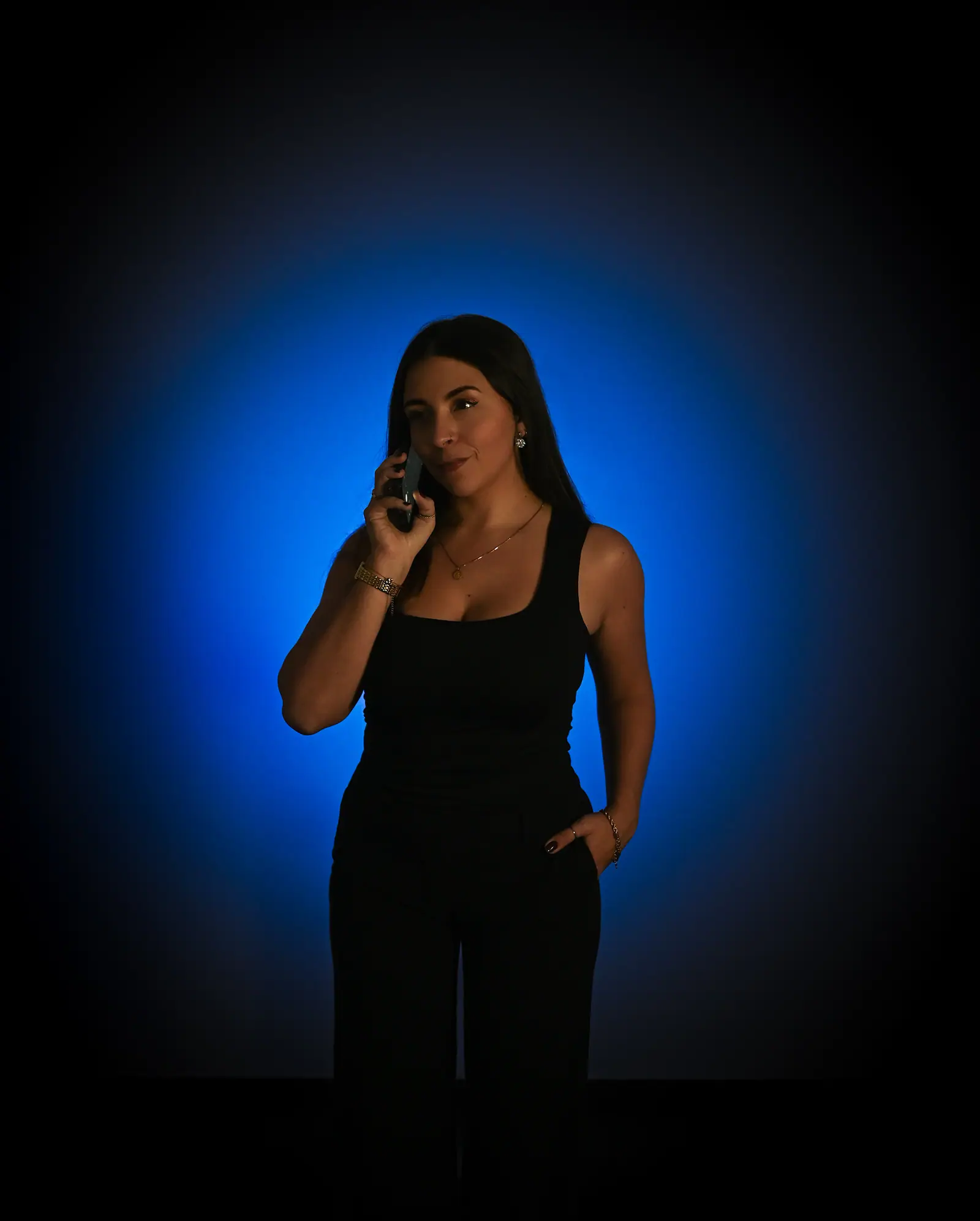 Woman in black on the phone, framed by a blue halo of light