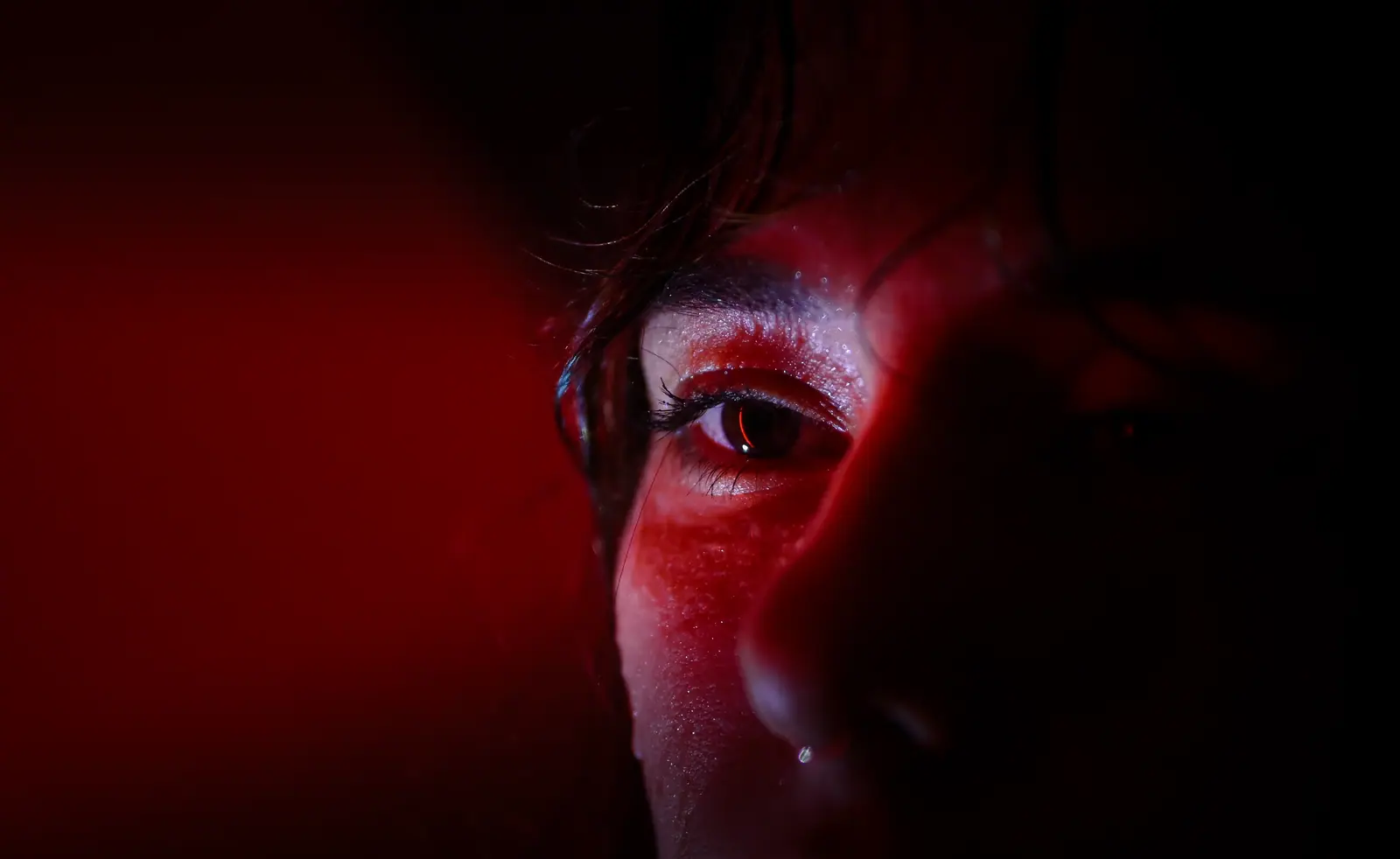 Extreme close-up of an eye, lit in deep red